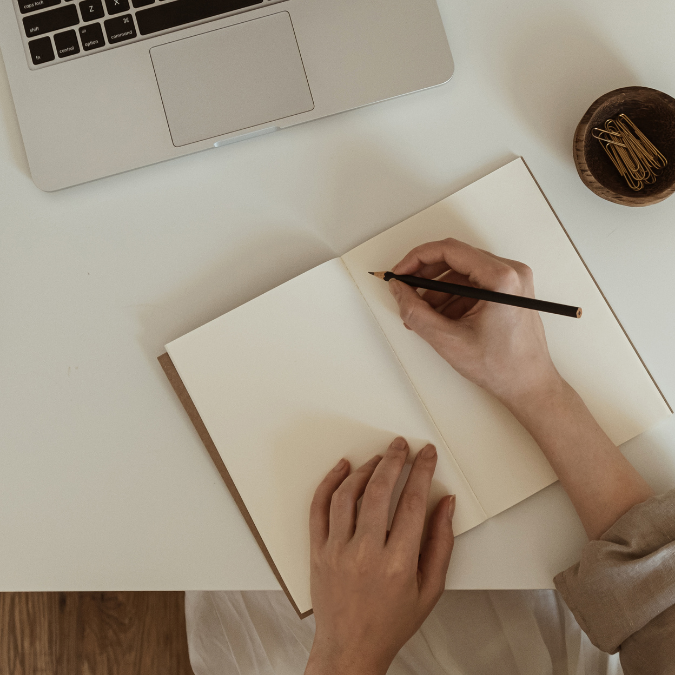 Pessoa a escrever num caderno num espaço de trabalho
